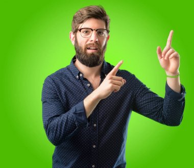 Yeşil arka plan üzerinde uzak yan parmak ile işaret büyük sakallı genç hipster adam