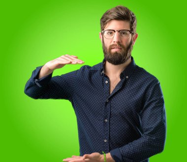 Bir şey boyutu kavram yeşil arka plan üzerinde tutan büyük sakallı genç hipster adam