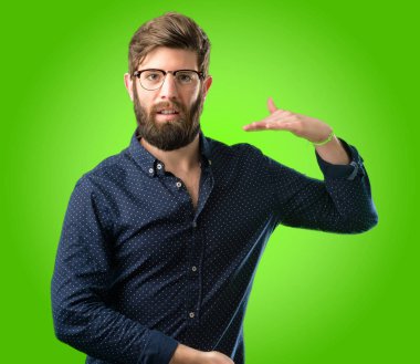 Bir şey boyutu kavram yeşil arka plan üzerinde tutan büyük sakallı genç hipster adam