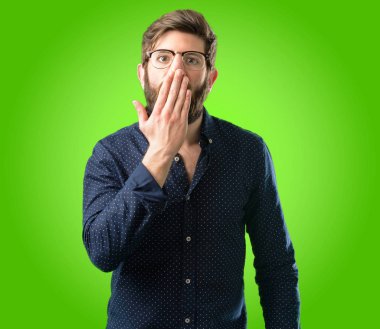 Büyük sakallı genç hipster adam şok ağzına kapakları, sessizlik ve hata kavramlar, yeşil arka plan üzerinde korkmuş ifade utangaç, görünüyor