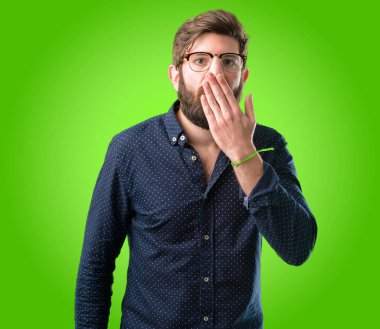 Büyük sakallı genç hipster adam şok ağzına kapakları, sessizlik ve hata kavramlar, yeşil arka plan üzerinde korkmuş ifade utangaç, görünüyor