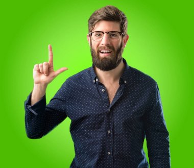 Yeşil arka plan üzerinde uzak yan parmak ile işaret büyük sakallı genç hipster adam