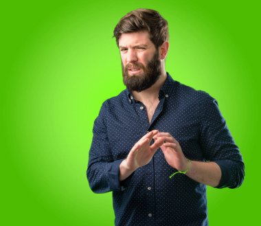 Tiksinti ve kızgın, büyük sakallı genç hipster adam ellerini dur hareketle bir savunma olarak, yeşil arka plan üzerinde bağırarak tutmak