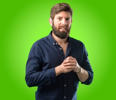 Kendinden emin ve mutlu yeşil arka plan üzerinde büyük bir doğal gülümseme ile büyük sakallı genç hipster adam