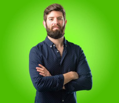 Kendinden emin ve mutlu bir büyük doğal ile çapraz kollu büyük sakallı genç hipster adam gülümseme yeşil arka plan üzerinde gülüyor
