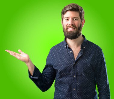 Bir şey yeşil arka plan üzerinde boş elinde tutan büyük sakallı genç hipster adam