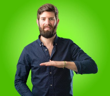 Bir şey boyutu kavram yeşil arka plan üzerinde tutan büyük sakallı genç hipster adam