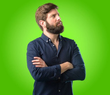 Kendinden emin ve mutlu bir büyük doğal ile çapraz kollu büyük sakallı genç hipster adam gülümseme yeşil arka plan üzerinde gülüyor