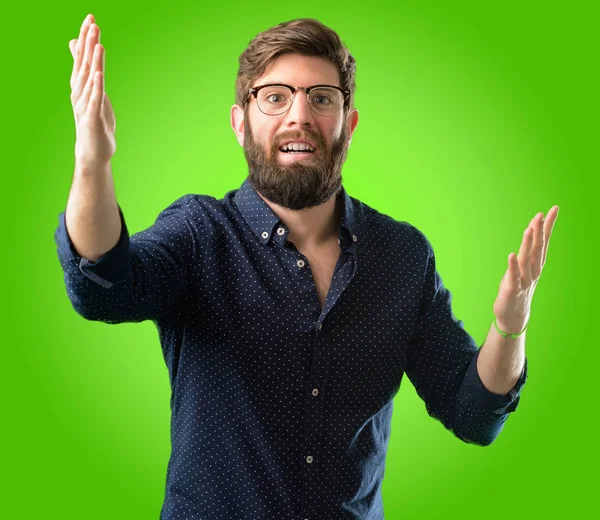 Kendinden emin ve mutlu yeşil arka plan üzerinde bir büyük doğal gülümseme hoş geldiniz hareketi ile büyük sakallı genç hipster adam