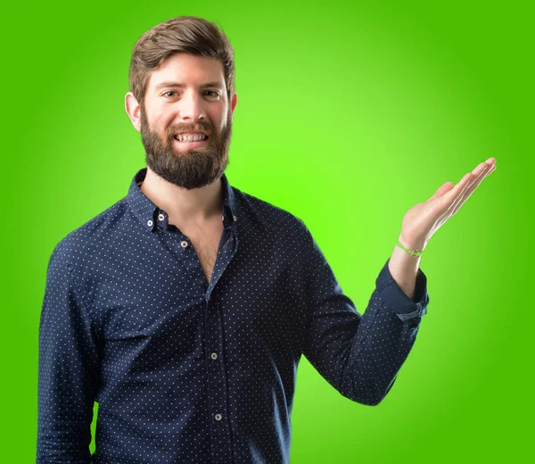 Bir şey yeşil arka plan üzerinde boş elinde tutan büyük sakallı genç hipster adam