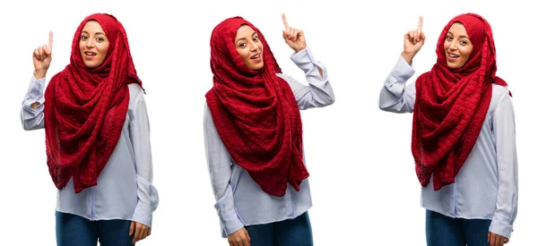 戴头巾的阿拉伯妇女高兴和惊讶欢呼表达的哇手势指向孤立的白色背景 — 图库照片