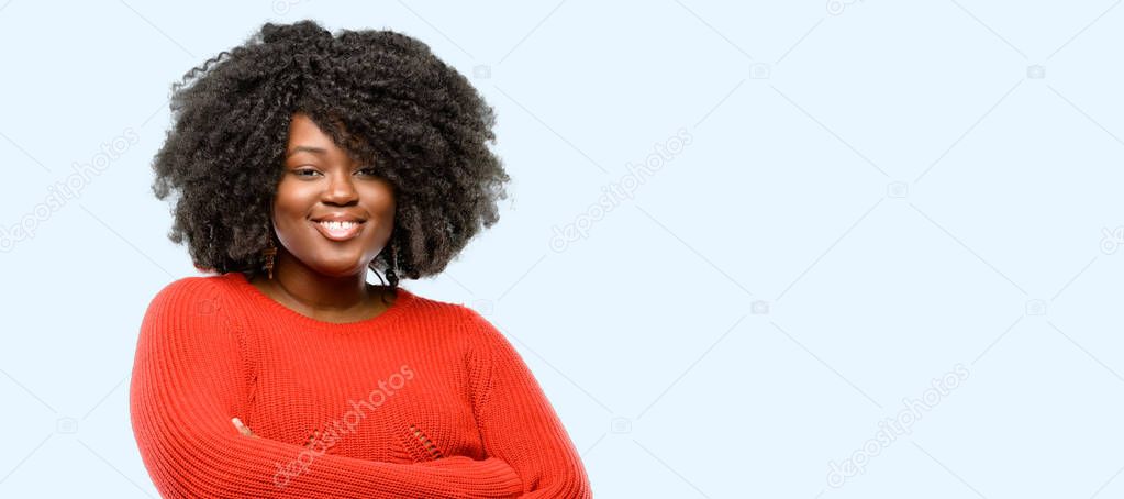 Beautiful african woman with crossed arms confident and happy with a big natural smile laughing, blue background