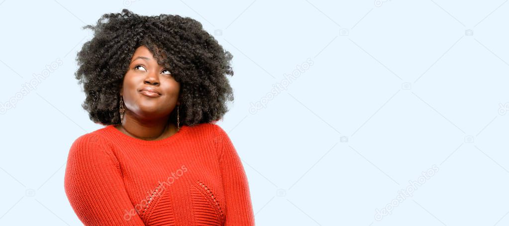 Beautiful african woman confident and happy with a big natural smile laughing looking up, blue background