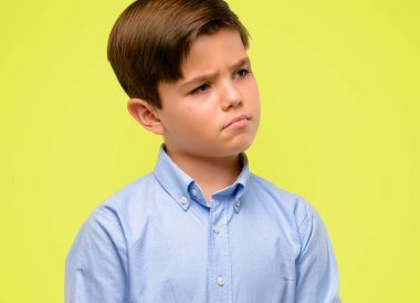 Yeşil gözlü yakışıklı yürümeye başlayan çocuk ifade şüphe, şaşırtmak ve kavramı, sarı arka plan üzerinde belirsiz gelecek merak ediyorum