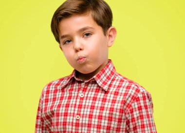 Yanakları şişirme yeşil gözlü yakışıklı yürümeye başlayan çocuk sarı arka plan üzerinde yüz komik yapma eğleniyor