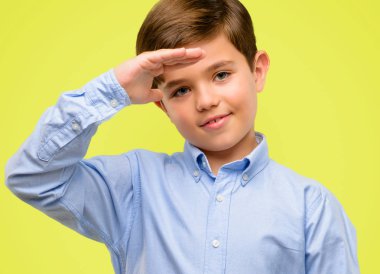 Bir şey boyutu kavram sarı arka plan üzerinde tutan yeşil gözlü yakışıklı yürümeye başlayan çocuk