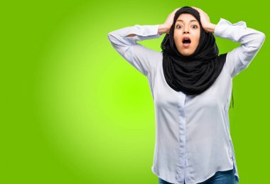 Genç Arap kadın giyiyor hijab stresli tutmak ellerinde kafa, panik, korku içinde bağırarak