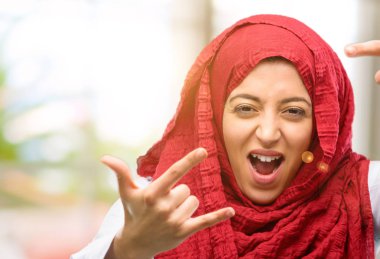 Rock simge elle yapma, bağırarak ve kutlama hijab giyen genç Arap kadın