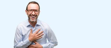 Kendinden emin ve mutlu mavi arka plan üzerinde izole gülüyor büyük bir doğal gülümseme ile gözlüklü adam orta yaş