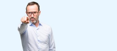 Gözlüklü önüne mavi arka plan üzerinde izole parmak ile işaret orta yaş adam