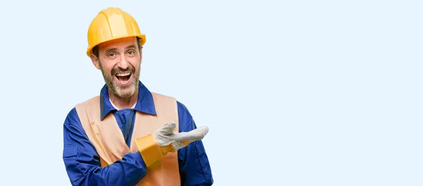 青い背景に分離されたシニア エンジニア男 空の手で何かを保持している建設労働者 — ストック写真