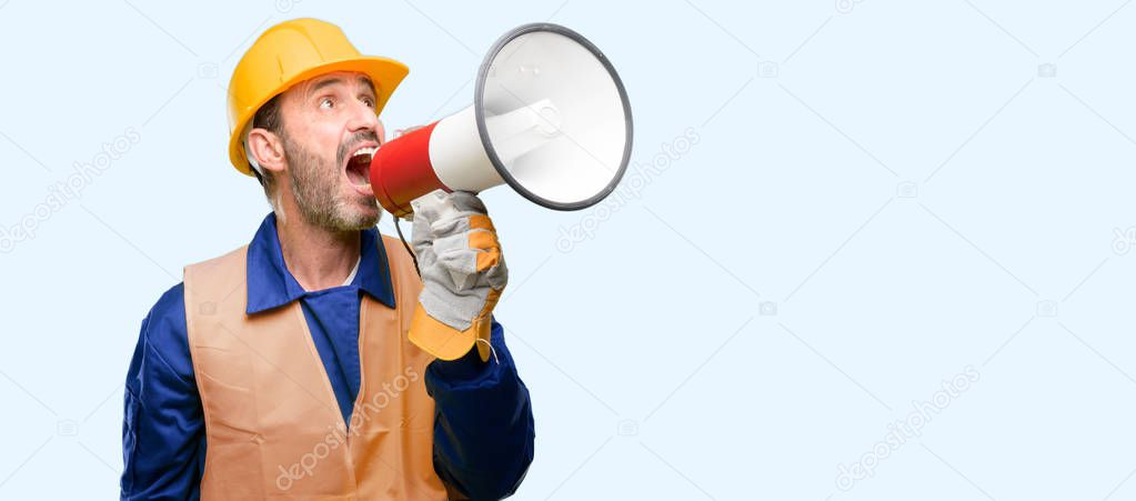 Senior engineer man, construction worker communicates shouting loud holding a megaphone, expressing success and positive concept, idea for marketing or sales isolated over blue background