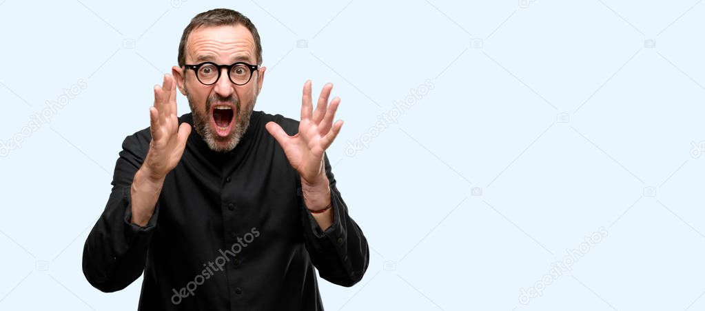 Priest religion man stressful keeping hands on head, terrified in panic, shouting isolated over blue background
