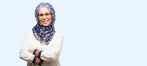 中世纪穆斯林阿拉伯妇女戴着头巾与交叉双臂自信和快乐的大自然微笑笑孤立蓝色背景 — 图库照片