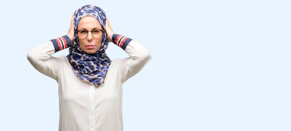 中世纪穆斯林阿拉伯妇女戴头巾捂住耳朵 不理会恼人的吵闹声 塞住耳朵以免听到声音 吵闹的音乐是个问题 独立的蓝色背景 — 图库照片