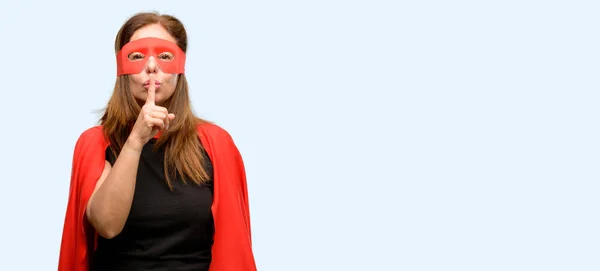 中年超级英雄女人戴着红色面具和披肩 手指在唇上 要求安静 沉默和秘密概念孤立的蓝色背景 — 图库照片