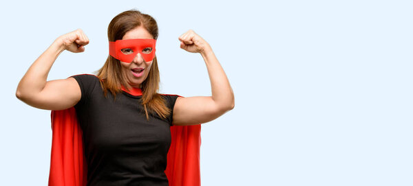 Middle age super hero woman wearing red mask and cape happy and excited celebrating victory expressing big success, power, energy and positive emotions. Celebrates new job joyful isolated blue background