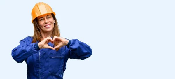 エンジニア建設労働者の女性の幸せと愛を示す手のハート形状表現健康と結婚の分離記号の青色の背景 — ストック写真