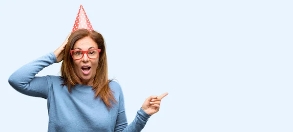 Mujer Mediana Edad Celebra Cumpleaños Apuntando Hacia Lado Con Dedo —  Fotos de Stock