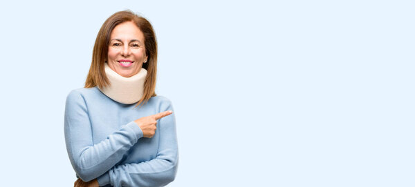 Injured woman wearing neck brace collar pointing away side with finger isolated blue background