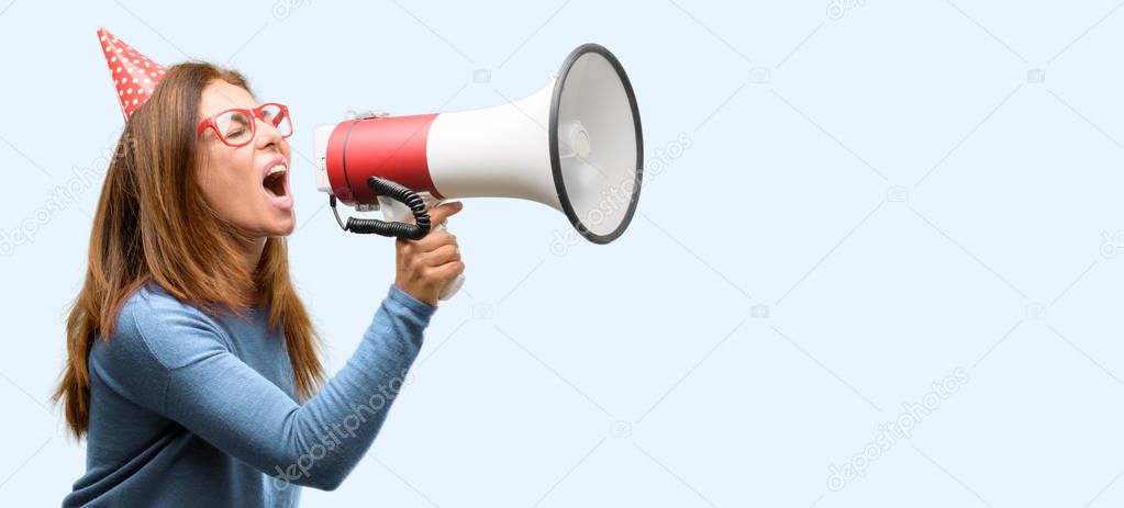 Middle age woman celebrates birthday communicates shouting loud holding a megaphone, expressing success and positive concept, idea for marketing or sales isolated blue background