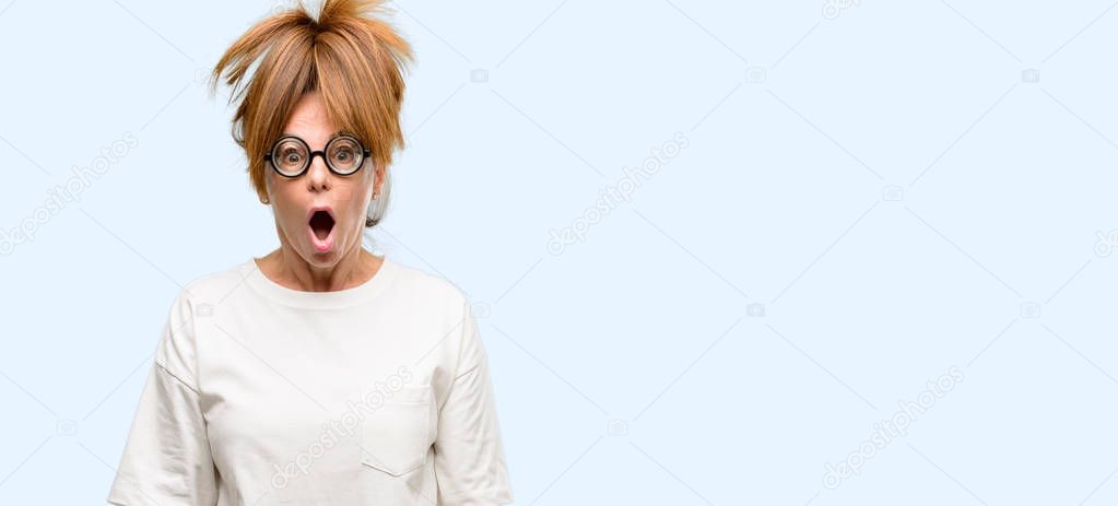 Crazy middle age woman wearing silly glasses scared in shock, expressing panic and fear isolated blue background