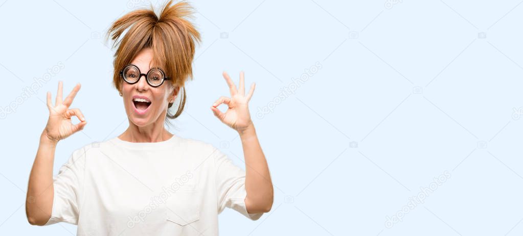 Crazy middle age woman wearing silly glasses doing ok sign gesture with both hands expressing meditation and relaxation isolated blue background