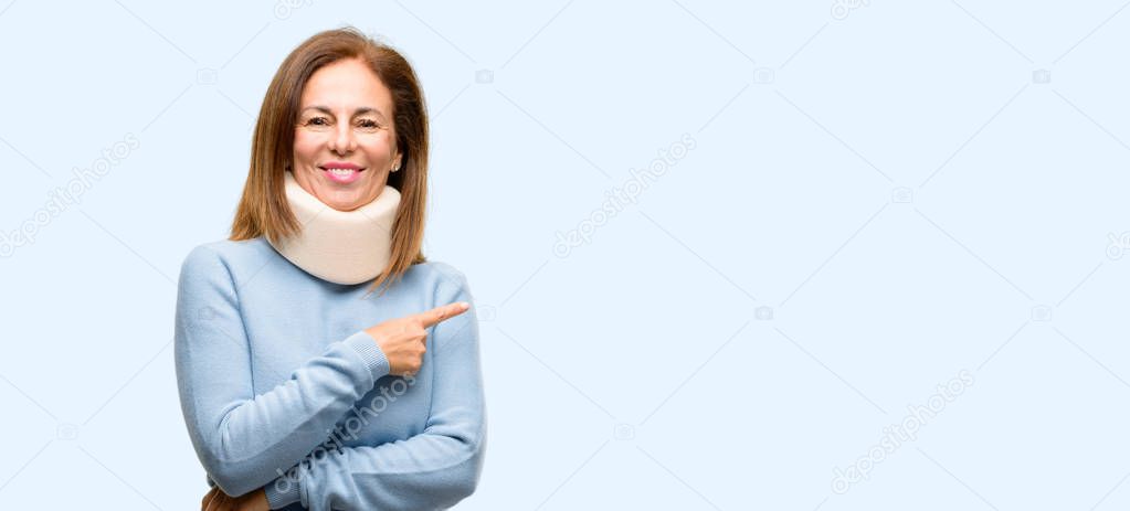 Injured woman wearing neck brace collar pointing away side with finger isolated blue background