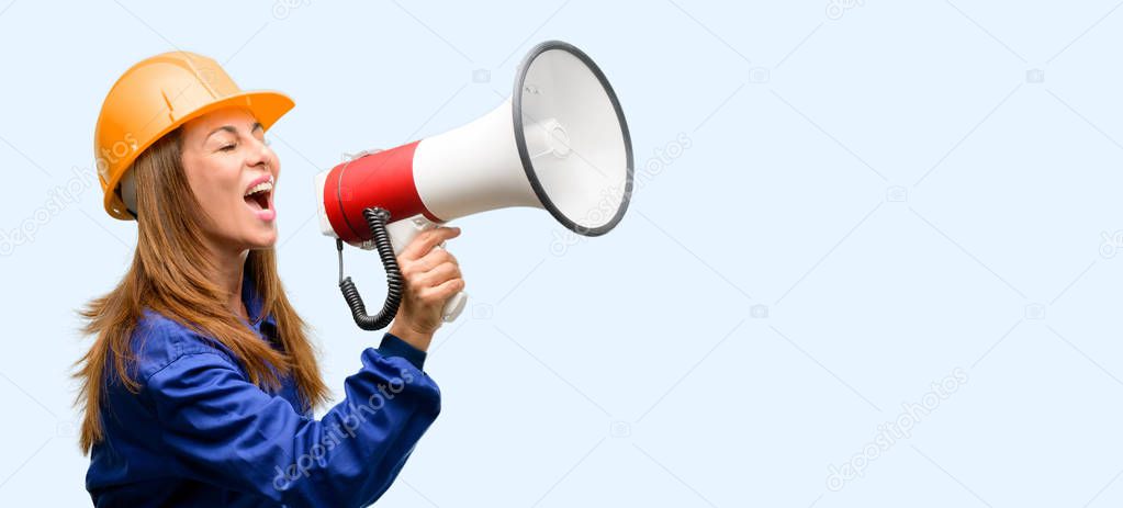 Engineer construction worker woman communicates shouting loud holding a megaphone, expressing success and positive concept, idea for marketing or sales isolated blue background