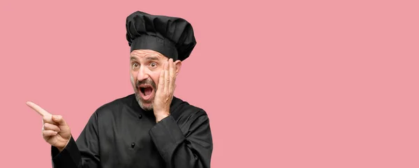 资深厨师人 戴着主厨帽指着一边用手指 — 图库照片