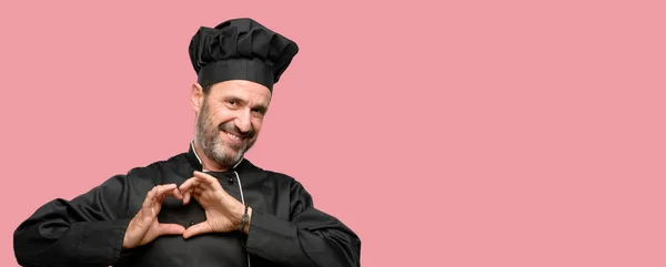 高级厨师 戴着厨师帽快乐地显示爱与手在心脏形状表达健康和婚姻标志 — 图库照片