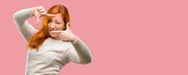 Güzel genç Kızıl saçlı kadın kendinden emin ve mutlu eller fotoğraf makinesi için gösterilen, beste ve jest çerçeveleme