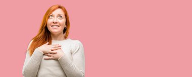 Çekici gülümseme sevgi ve sempati göstermek isteyen kalp üzerinde el ele tutuşarak sahip güzel genç Kızıl saçlı kadın