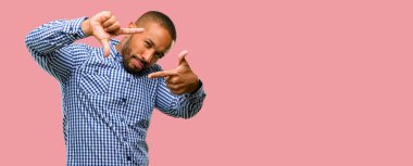 Kendinden emin ve mutlu eller fotoğraf makinesi için gösterilen, beste ve jest çerçeveleme sakallı Afrikalı-Amerikalı adam