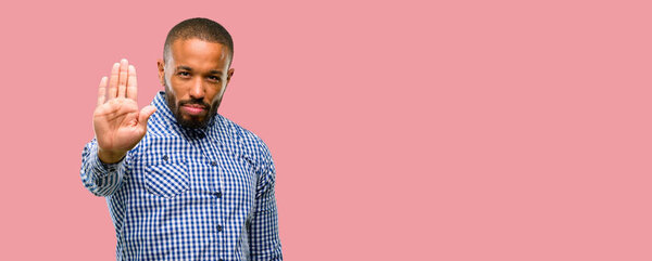 African american man with beard annoyed with bad attitude making stop sign with hand, saying no, expressing security, defense or restriction, maybe pushing