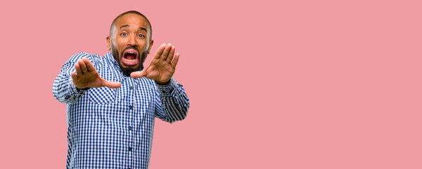 African american man with beard disgusted and angry, keeping hands in stop gesture, as a defense, shouting