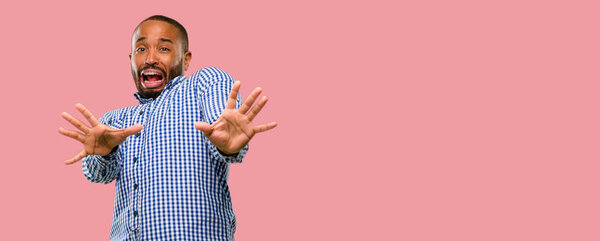 African american man with beard disgusted and angry, keeping hands in stop gesture, as a defense, shouting