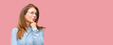 Orta yaş kadın yün kazak ve düşünme ve şüphe ve merak ifade arıyorsunuz serin gözlük