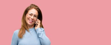 Yün kazak ve serin gözlük bir smartphone cep telefonu kullanarak konuşmak mutlu orta yaş kadın