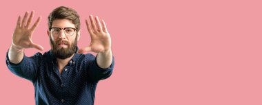 Kendinden emin ve mutlu eller fotoğraf makinesi için gösterilen, beste ve jest çerçeveleme büyük sakallı genç hipster adam